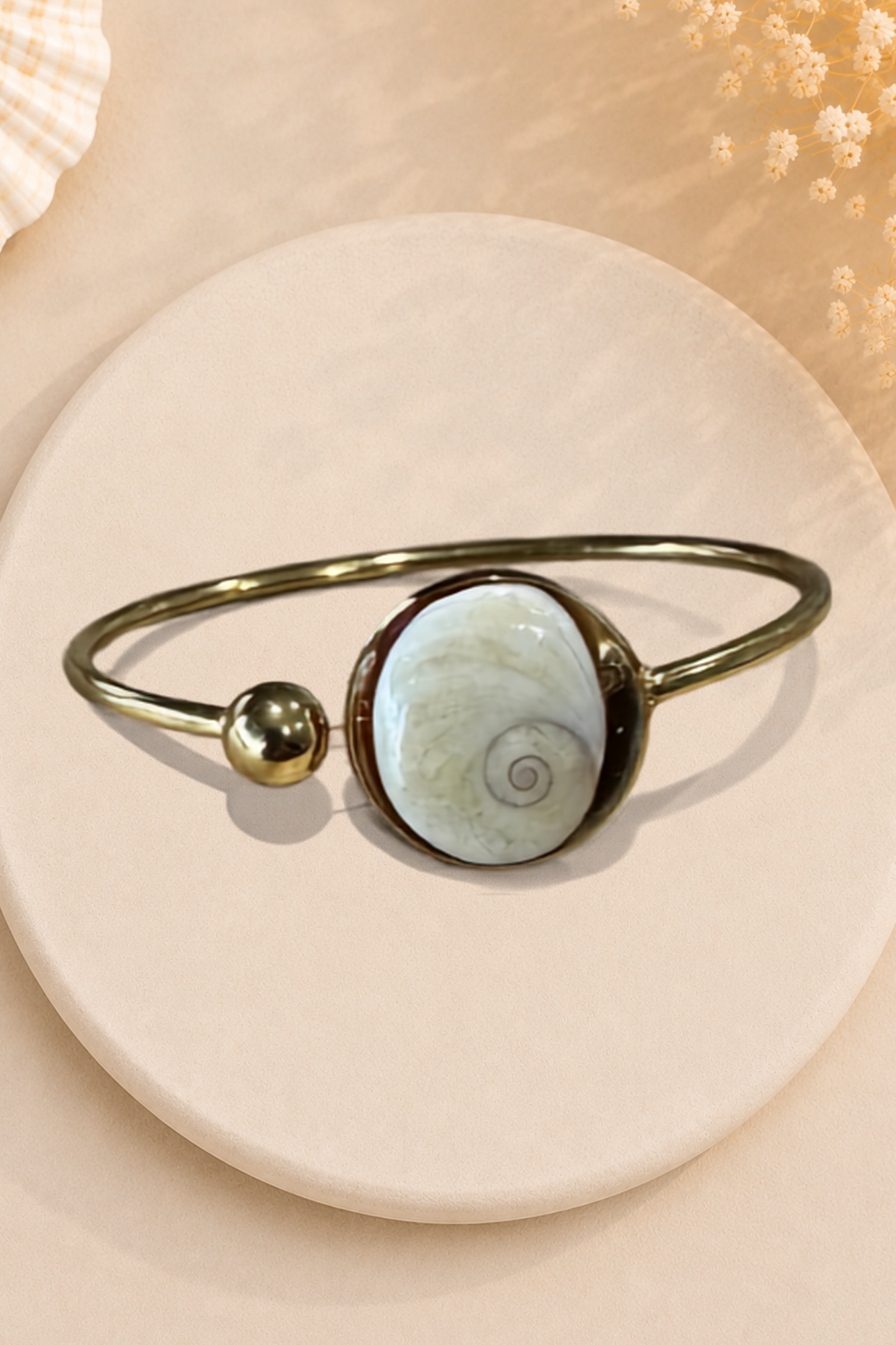 Bracelet jonc doré avec médaillon rond serti d'un Œil de Sainte-Lucie, style minimaliste marin.