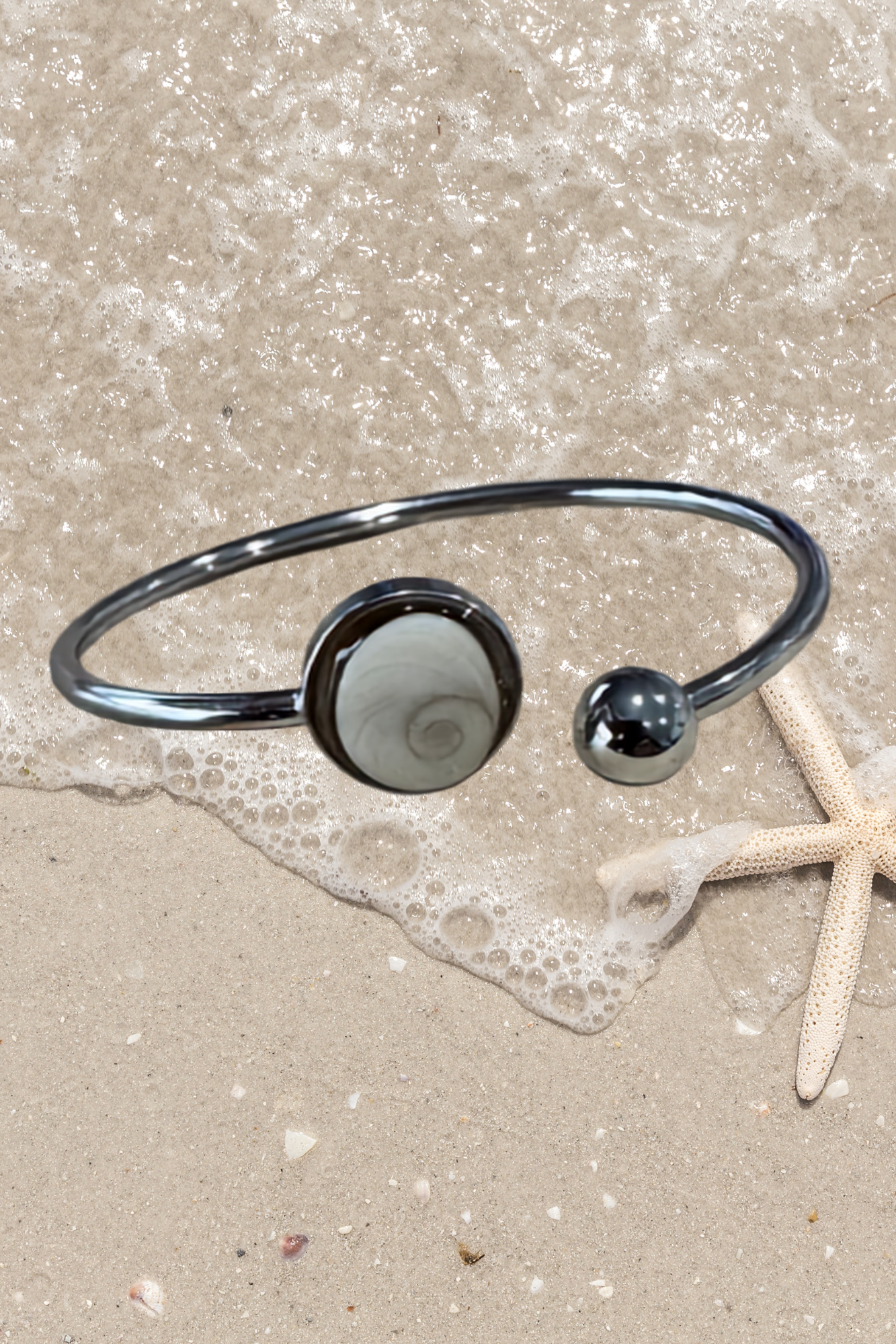 Bracelet jonc doré avec médaillon rond serti d'un Œil de Sainte-Lucie gris, style minimaliste marin.