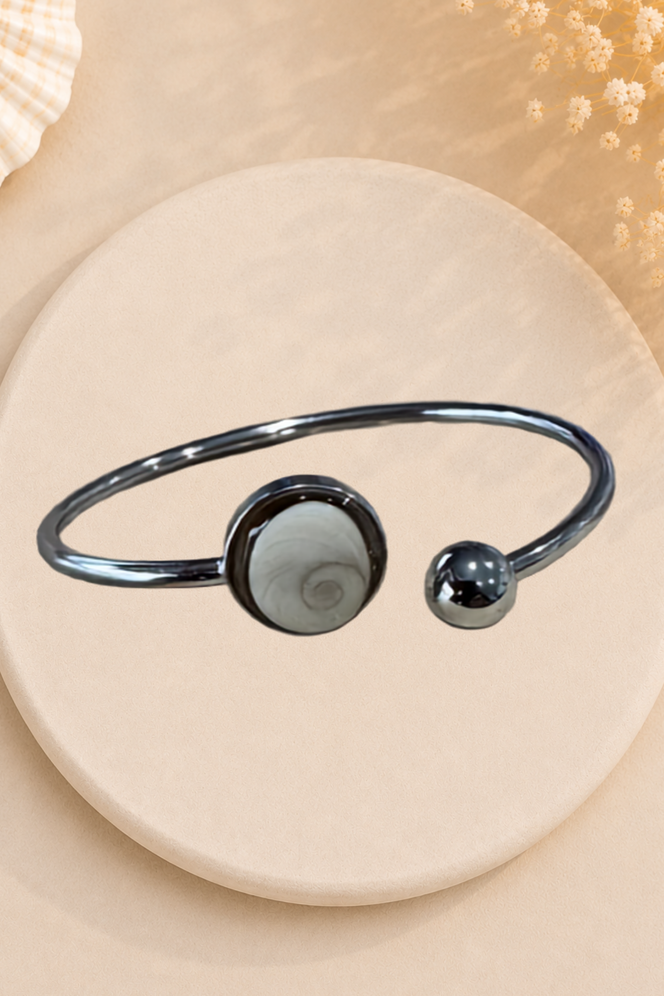 Bracelet jonc doré avec médaillon rond serti d'un Œil de Sainte-Lucie gris, style minimaliste marin.