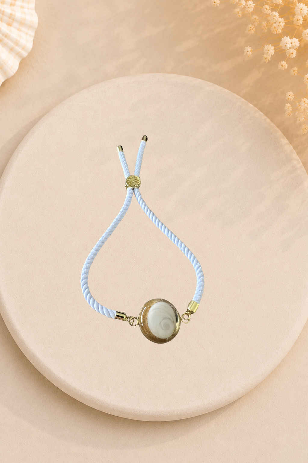 Bracelet femme Œil de Sainte‑Lucie sur cordon blanc et médaillon doré. Bijou artisanal, chic et porte‑bonheur méditerranéen, élégant au quotidien.