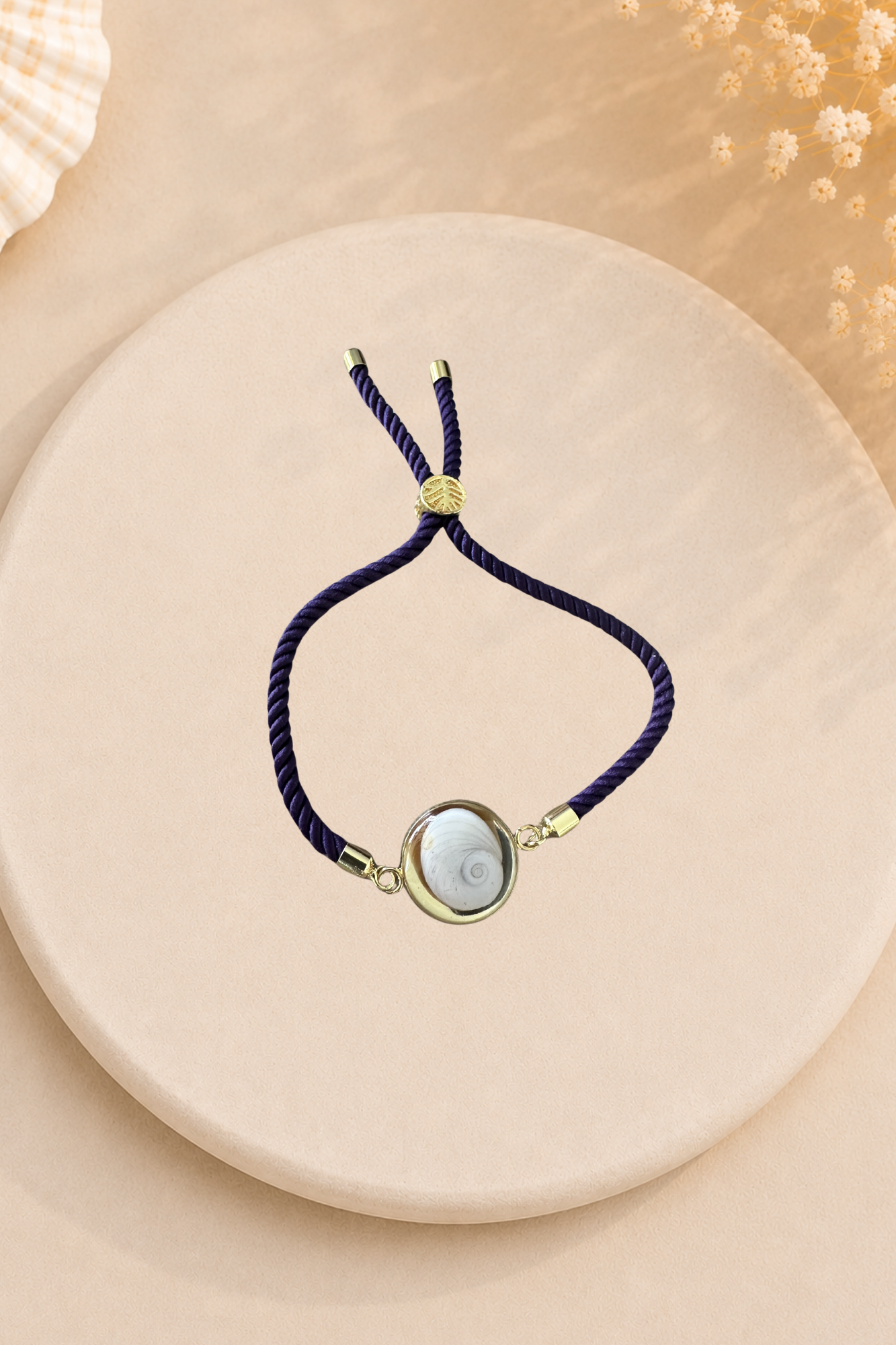 Bracelet femme Œil de Sainte‑Lucie sur cordon prune et médaillon doré. Bijou artisanal, chic et porte‑bonheur méditerranéen, élégant au quotidien.
