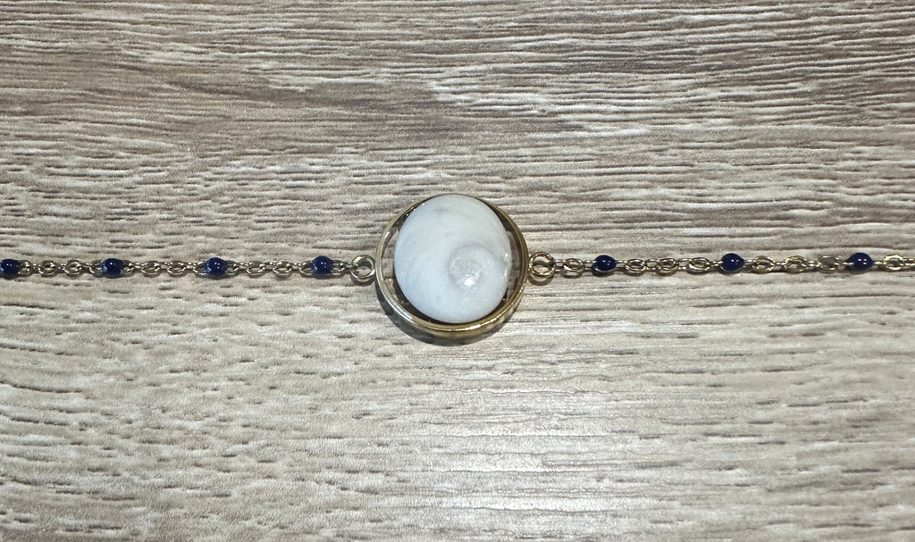 Gros plan sur le cabochon en Œil de Sainte-Lucie et les perles marine du bracelet Thetis