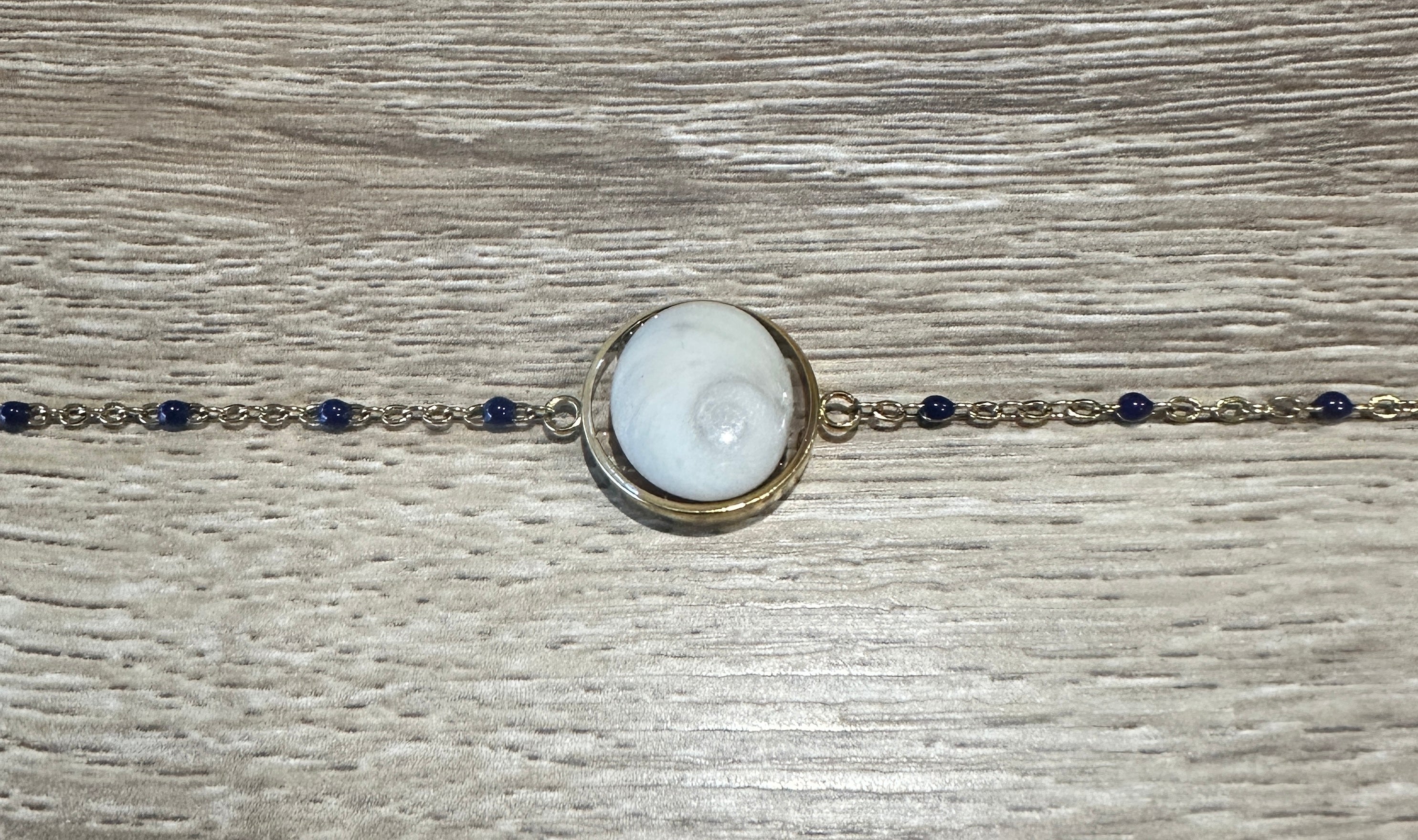 Gros plan sur le cabochon en Œil de Sainte-Lucie et les perles marine du bracelet Thetis