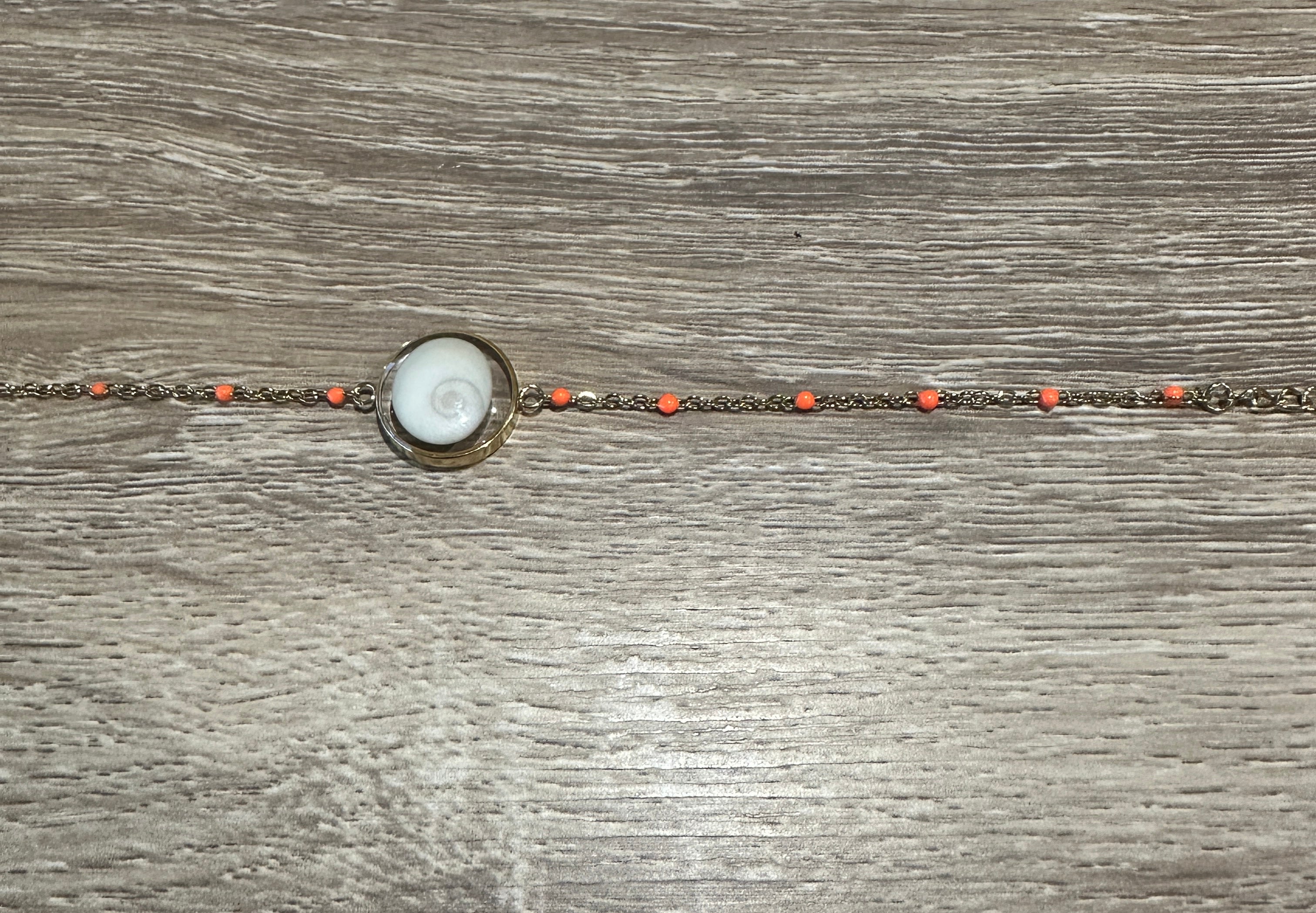 Gros plan sur le cabochon en Œil de Sainte-Lucie et les perles orange du bracelet Thetis