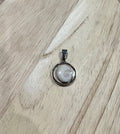 Gros plan sur le pendentif cabochon rond argenté serti d'un Oeil de Sainte-Lucie