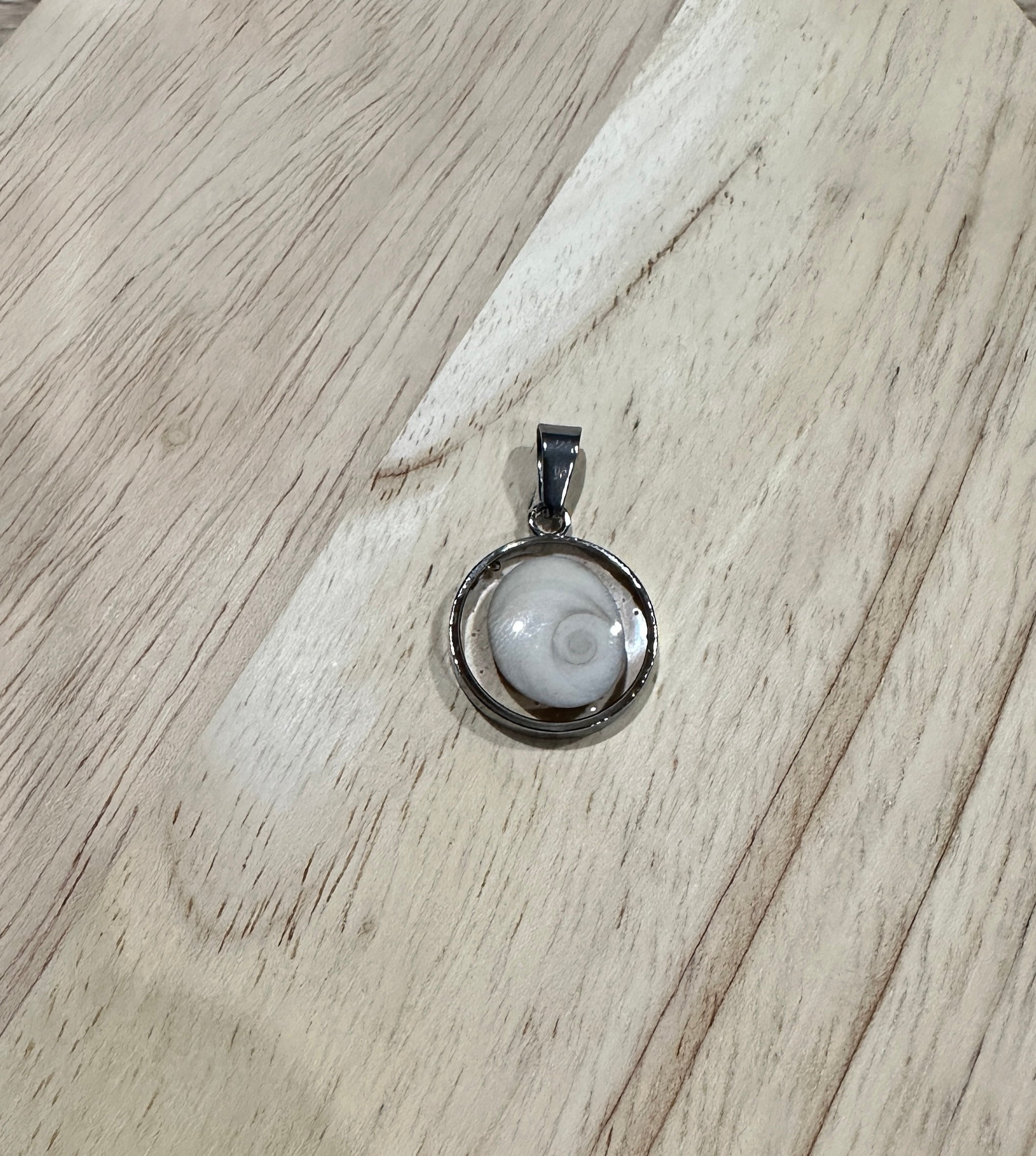 Gros plan sur le pendentif cabochon rond argenté serti d'un Oeil de Sainte-Lucie