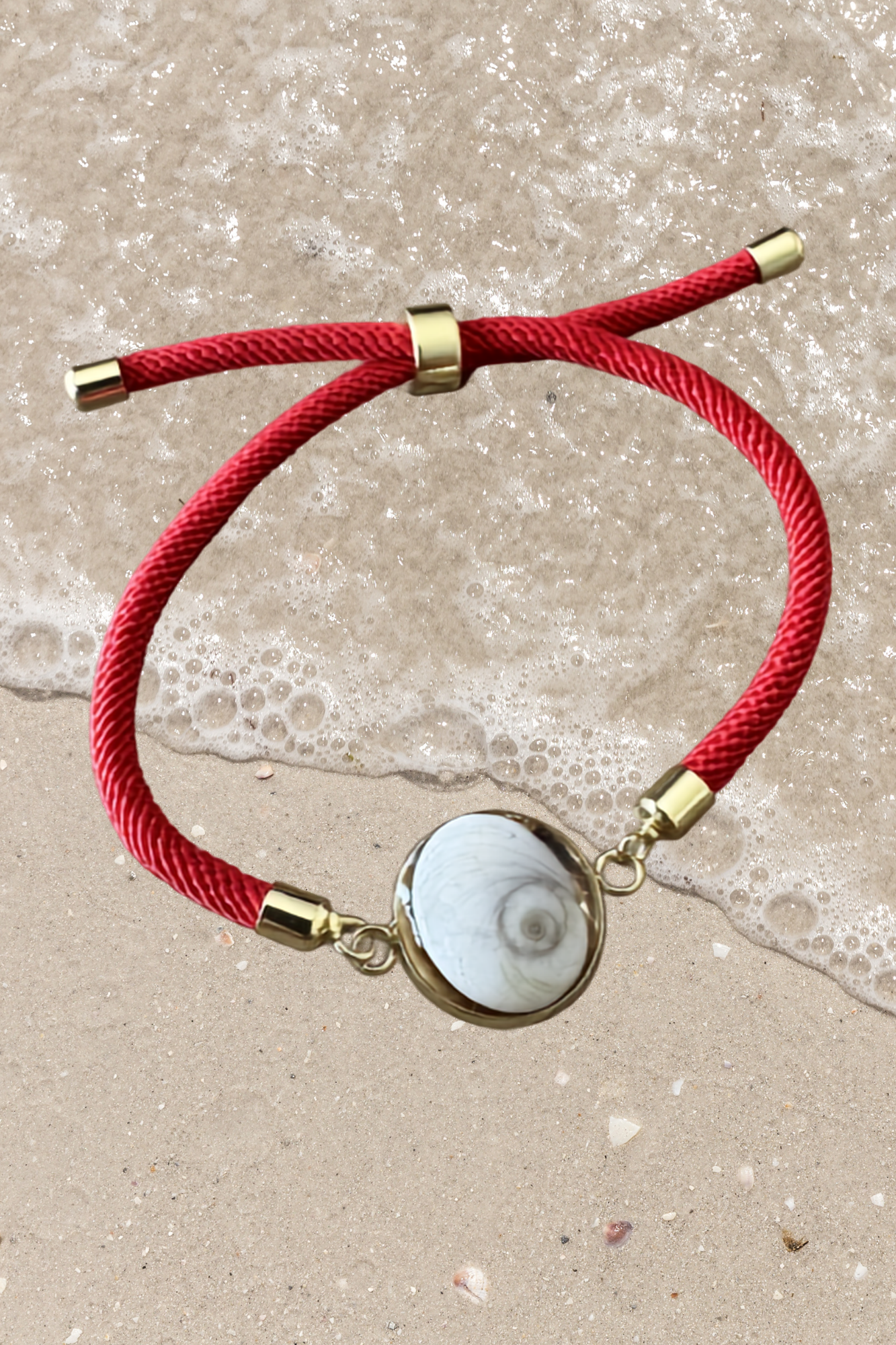 Bracelet femme, cordon rouge fin, médaillon rond doré serti d’un Œil de Sainte‑Lucie blanc, style chic et minimaliste.