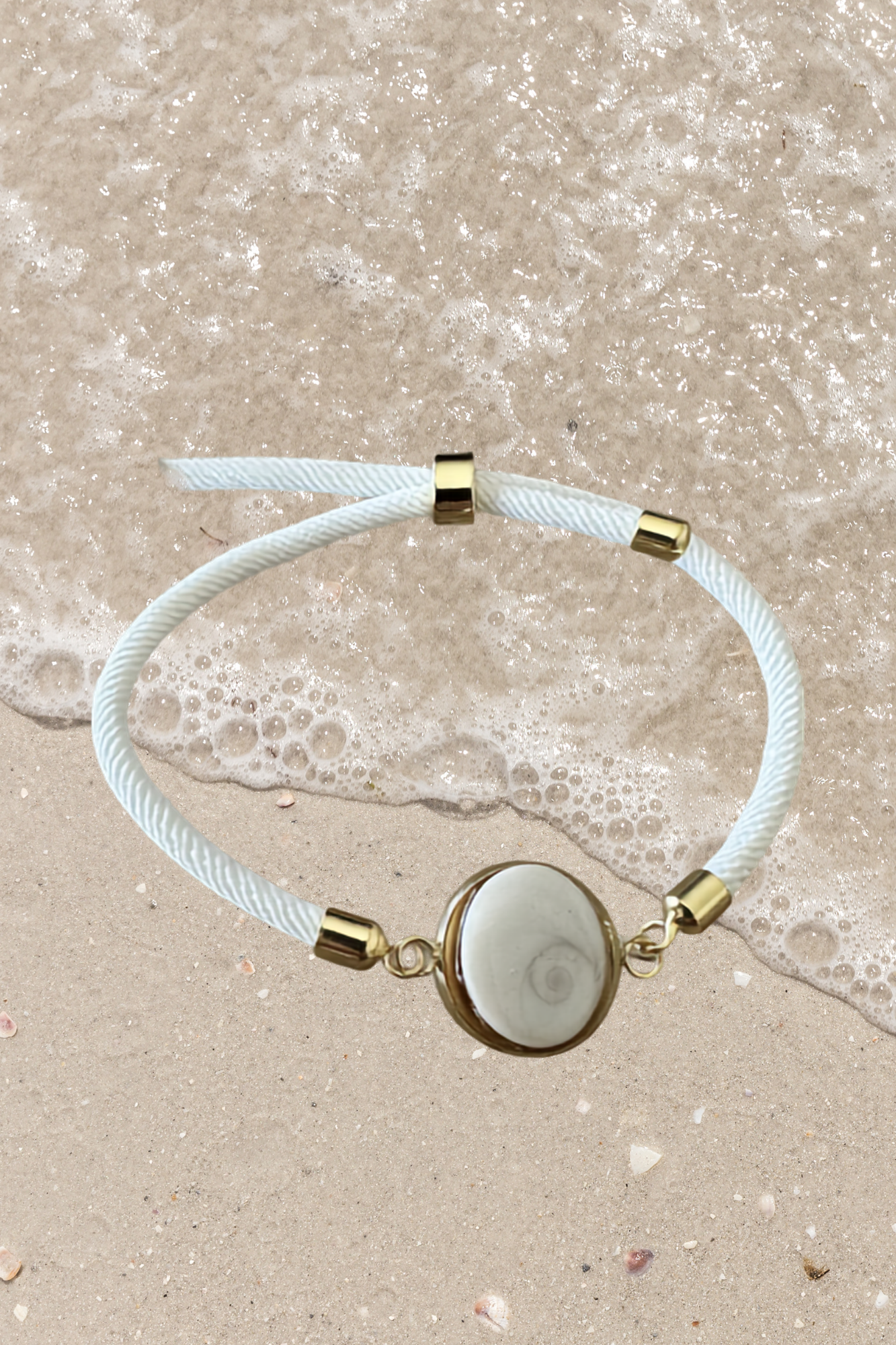 Bracelet femme, cordon blanc cassé fin, médaillon rond doré serti d’un Œil de Sainte‑Lucie blanc, style chic et minimaliste.