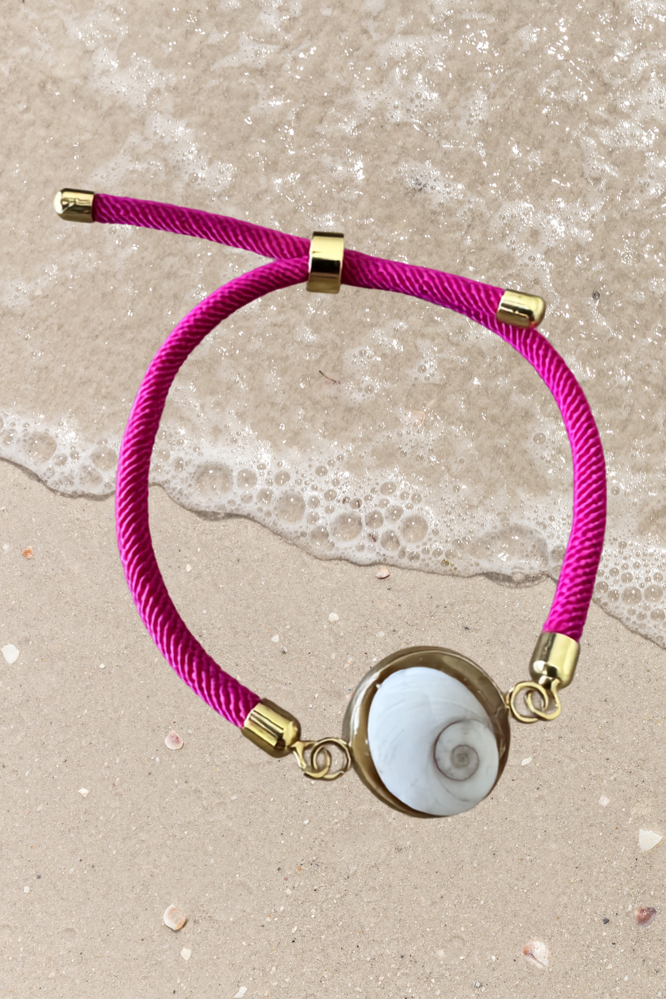 Bracelet femme, cordon fuchsia fin, médaillon rond doré serti d’un Œil de Sainte‑Lucie blanc, style chic et minimaliste.