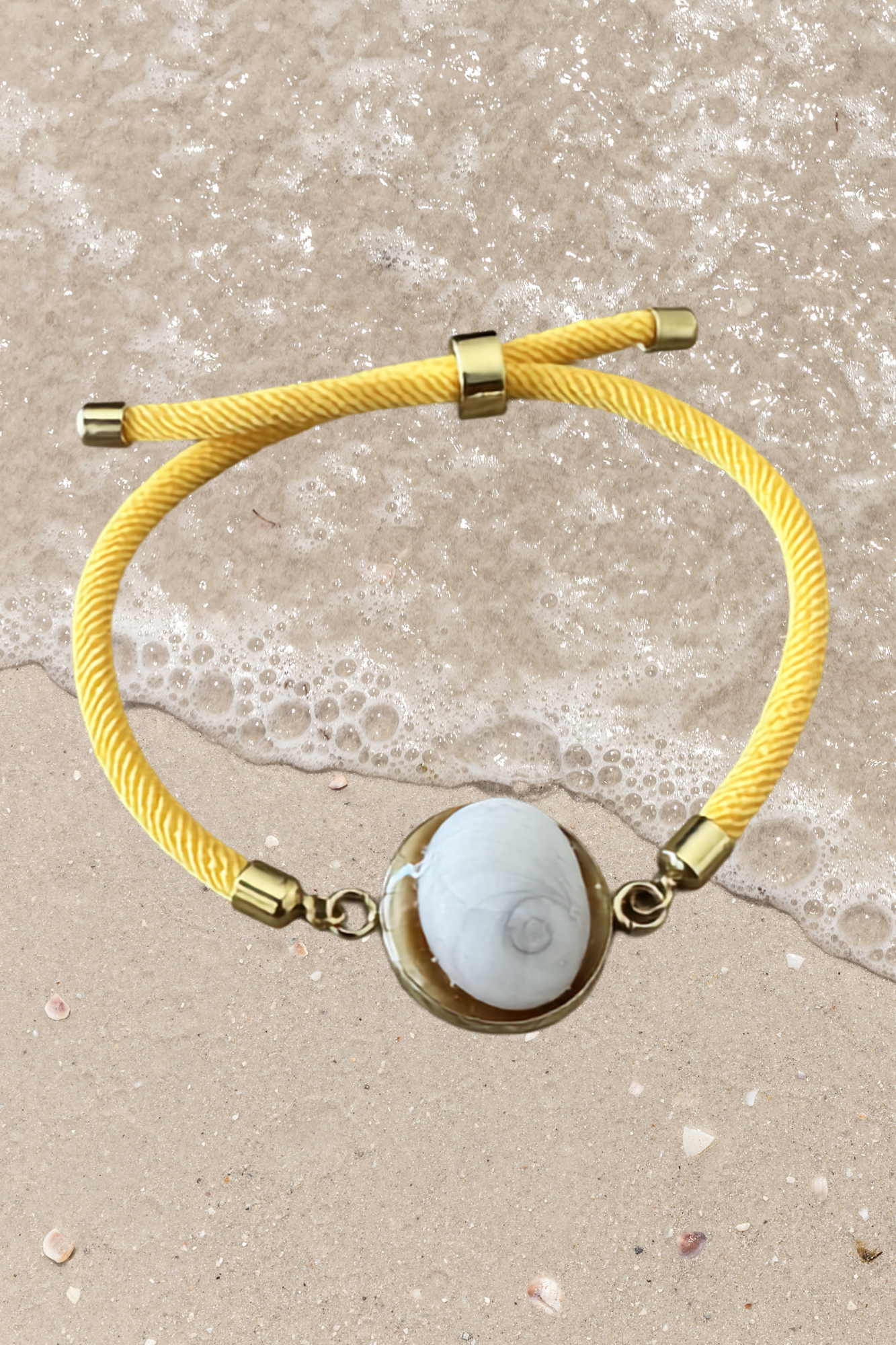 Bracelet femme, cordon jaune fin, médaillon rond doré serti d’un Œil de Sainte‑Lucie blanc, style chic et minimaliste.