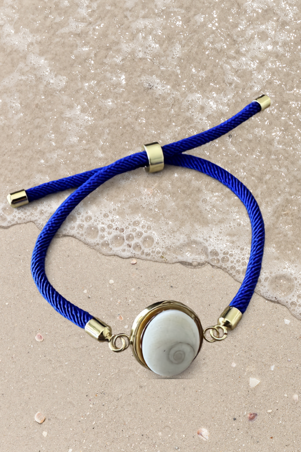 Bracelet femme, cordon bleu marine fin, médaillon rond doré serti d’un Œil de Sainte‑Lucie blanc, style chic et minimaliste.