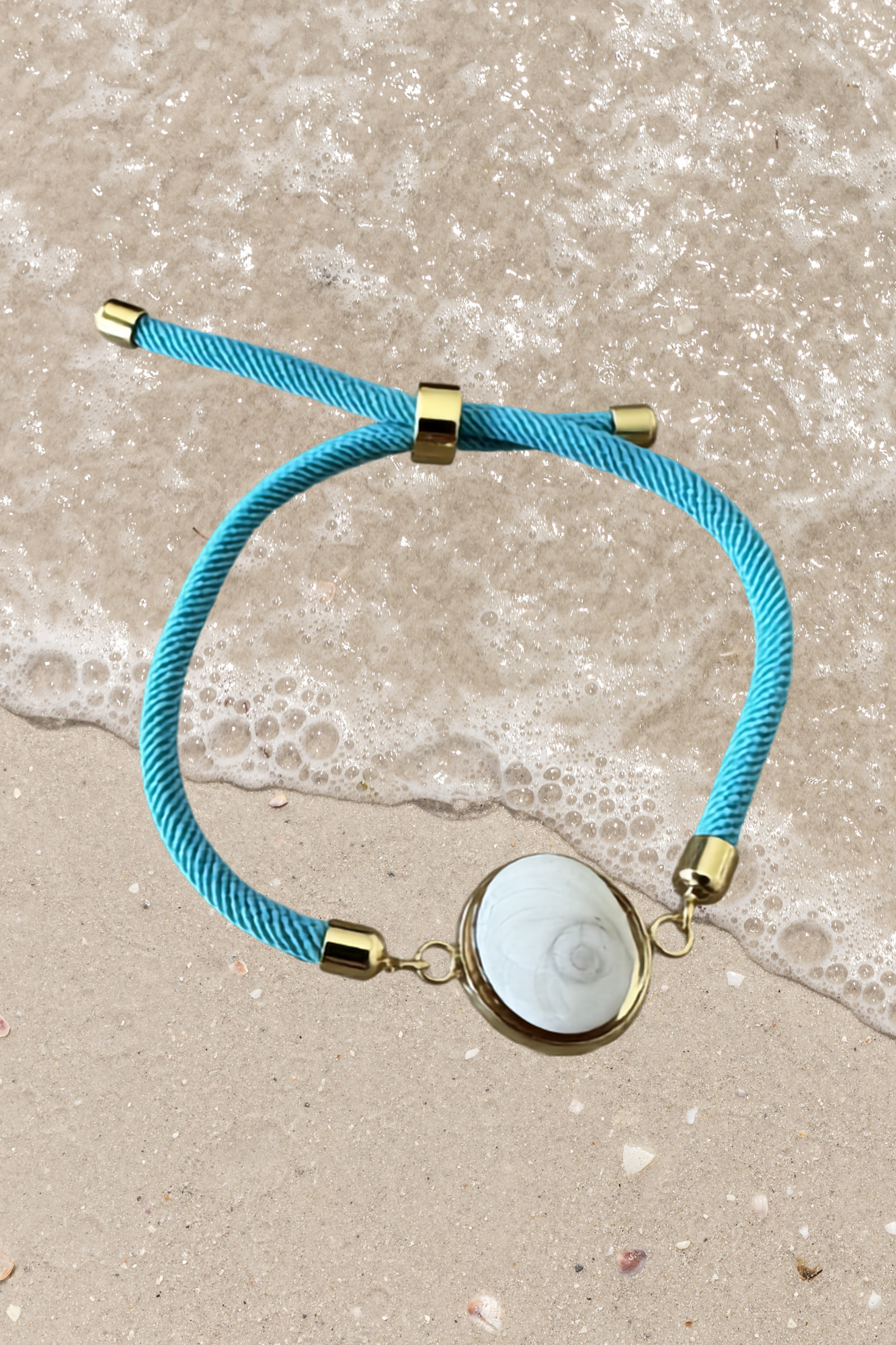Bracelet femme, cordon bleu turquoise fin, médaillon rond doré serti d’un Œil de Sainte‑Lucie blanc, style chic et minimaliste.
