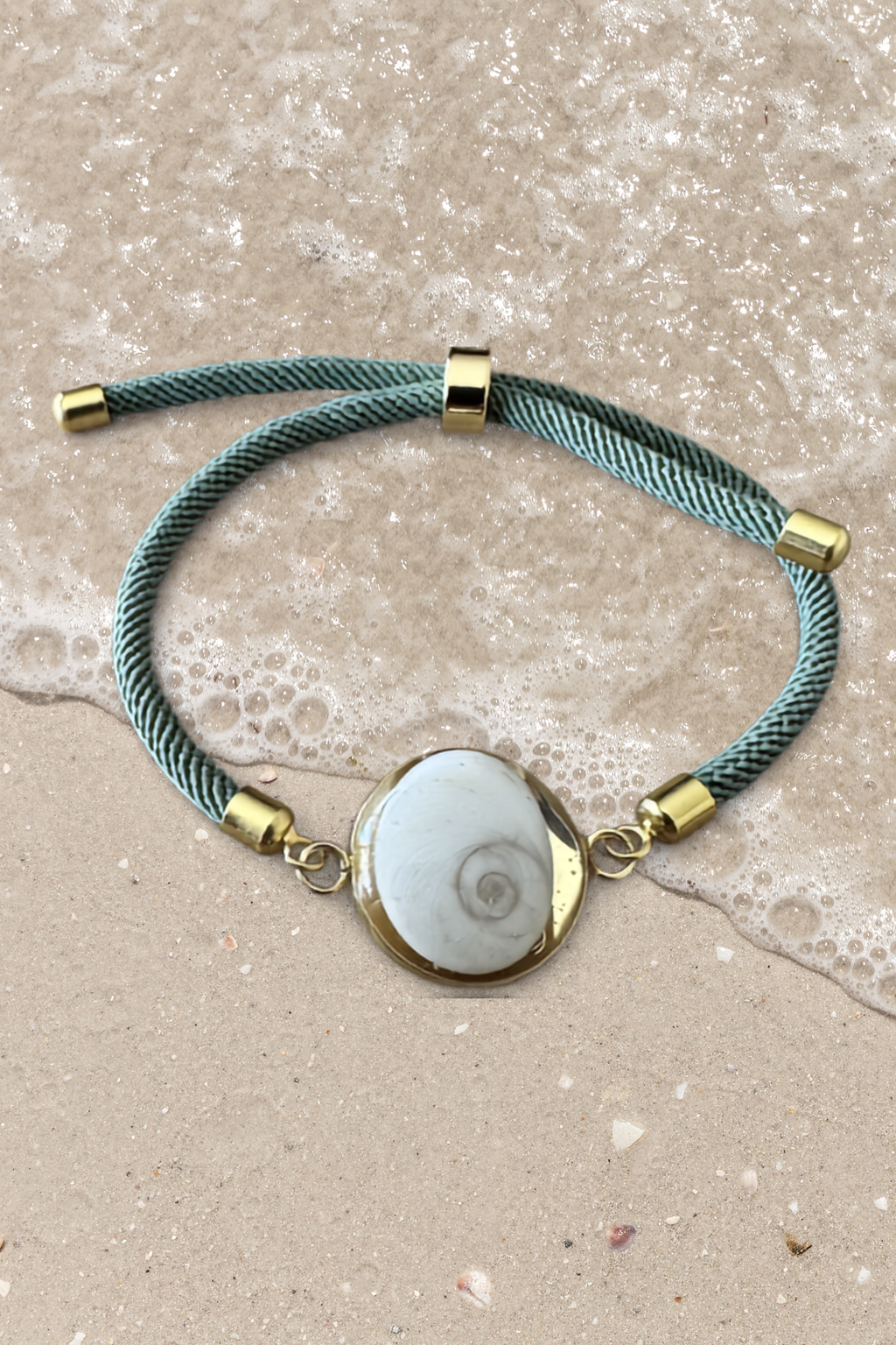 Bracelet femme, cordon vert d'eau fin, médaillon rond doré serti d’un Œil de Sainte‑Lucie blanc, style chic et minimaliste.