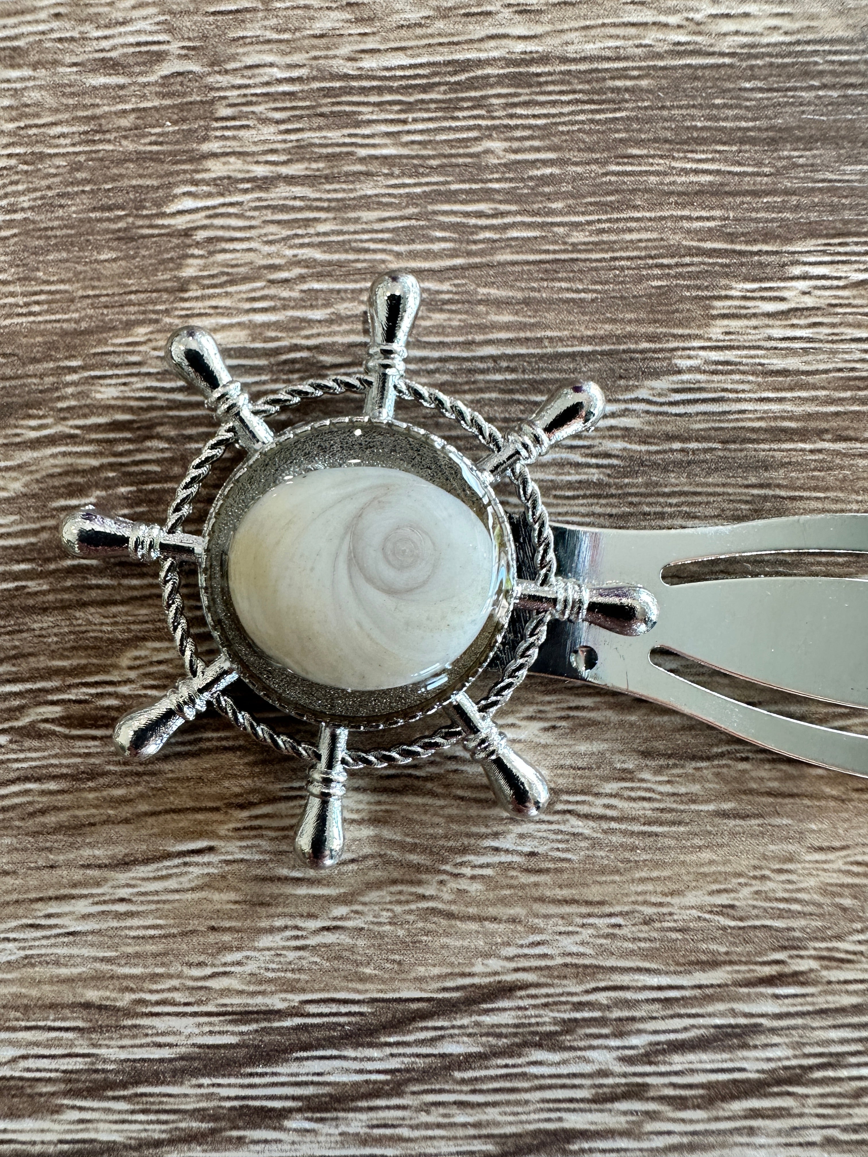 Gros plan sur le marque-page argenté en forme de gouvernail avec cabochon Œil de Sainte-Lucie