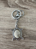 Porte-clés tortue argenté avec cabochon Œil de Sainte-Lucie brun, vue verticale
