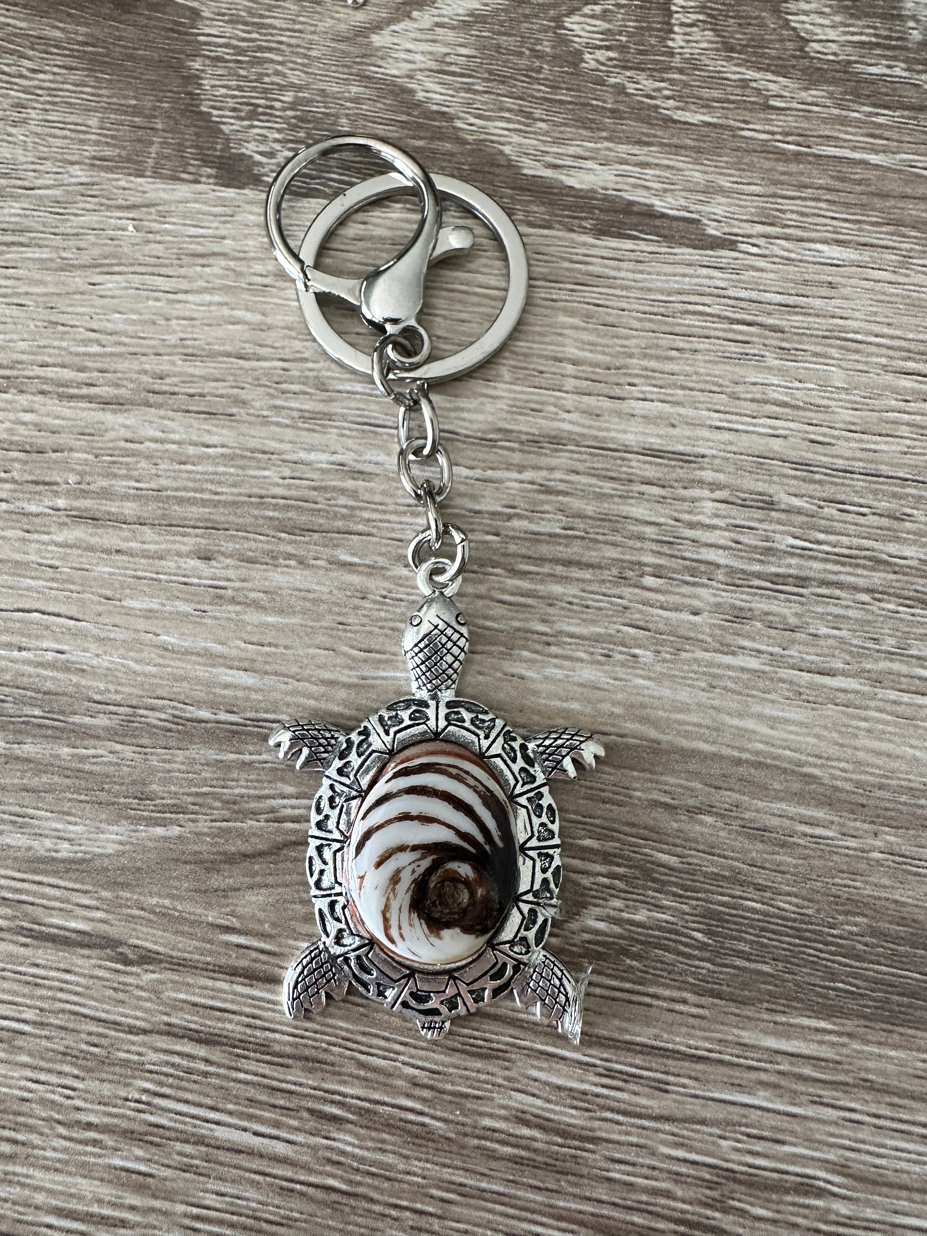 Gros plan sur le porte-clés tortue argenté avec cabochon Œil de Sainte-Lucie brun